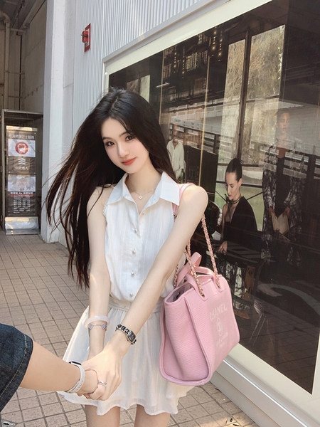 Woman wearing white sleeveless shirt dress and holding pink Chanel bag