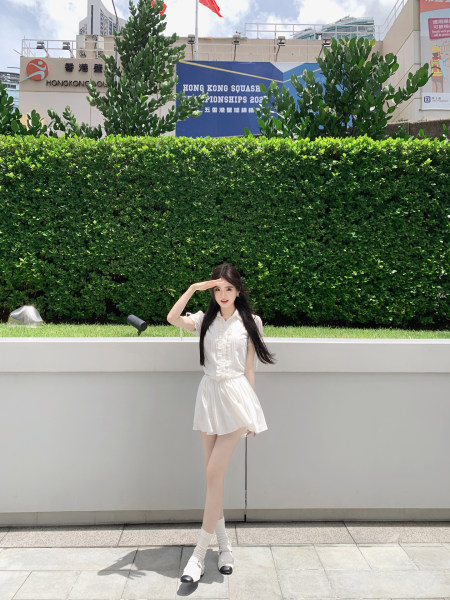 Woman wearing a white dress and white shoes posing outdoors