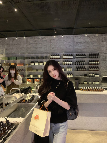Woman wearing black sweater and jeans in a store, holding a shopping bag