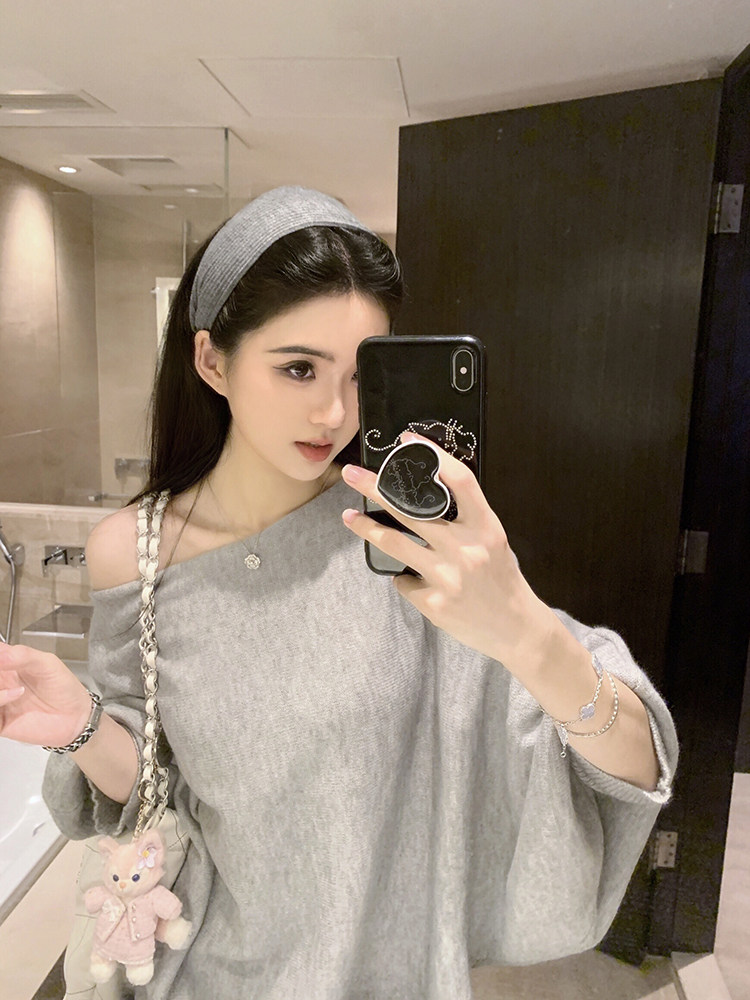 Woman taking mirror selfie wearing gray off-shoulder sweater and matching headband