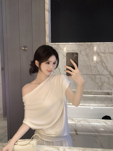 Woman taking mirror selfie wearing white one-shoulder top