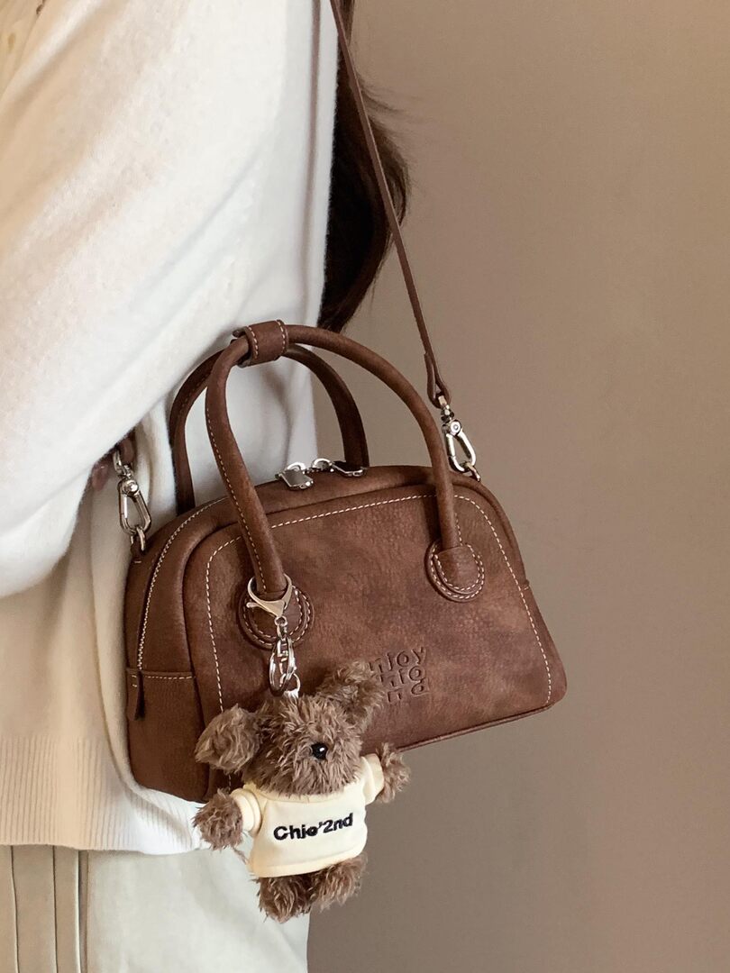 Brown leather handbag worn with teddy bear charm