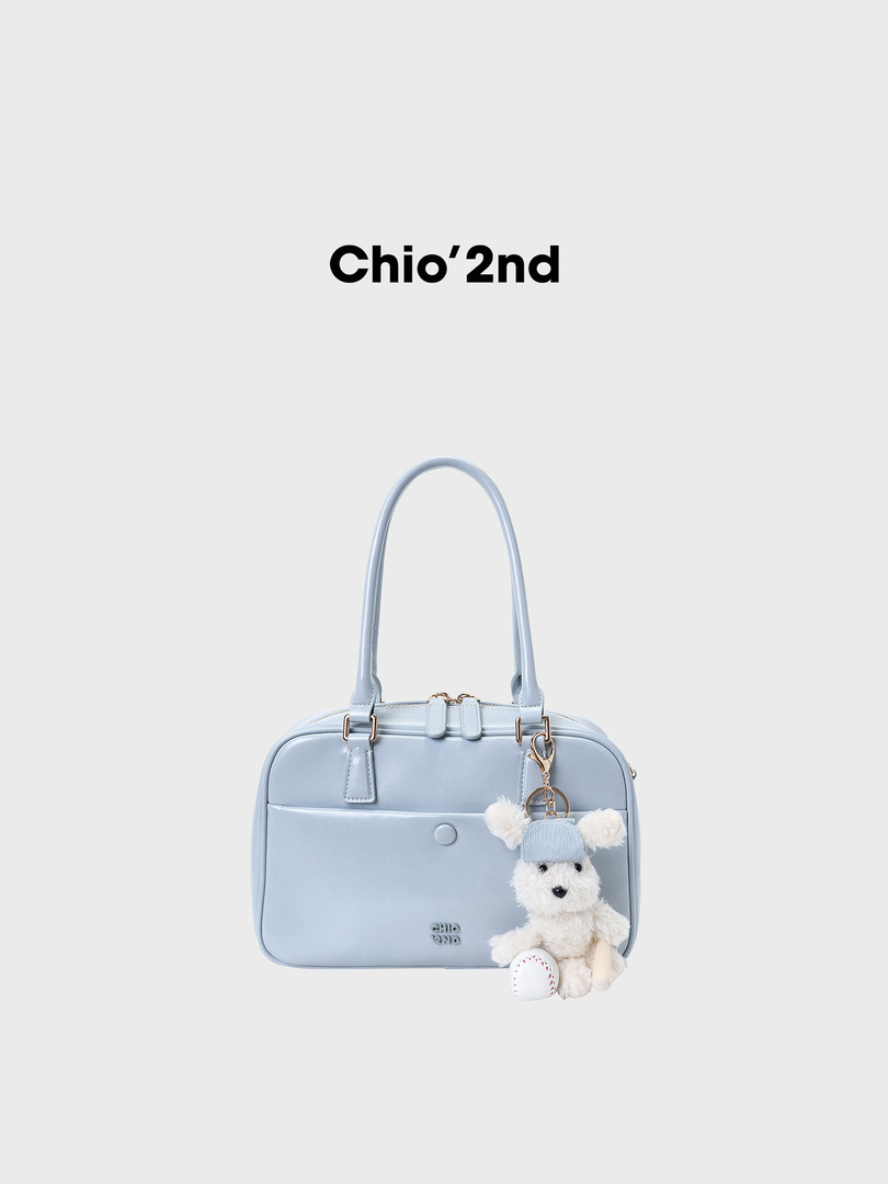 Light blue handbag with teddy bear charm on a white background