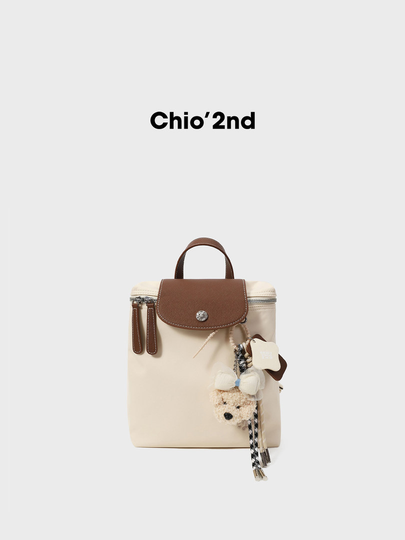 Beige and brown backpack with charm accessories on a white background