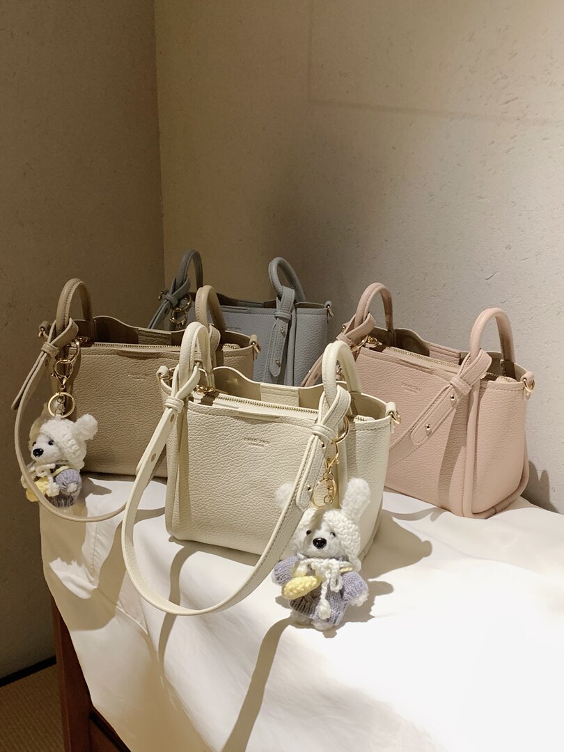 Collection of pastel textured handbags with teddy bear charms displayed on a table