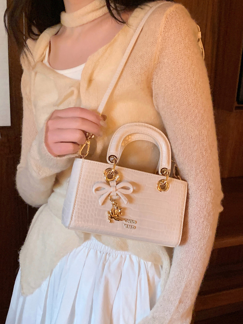 Light pink structured handbag worn by a model