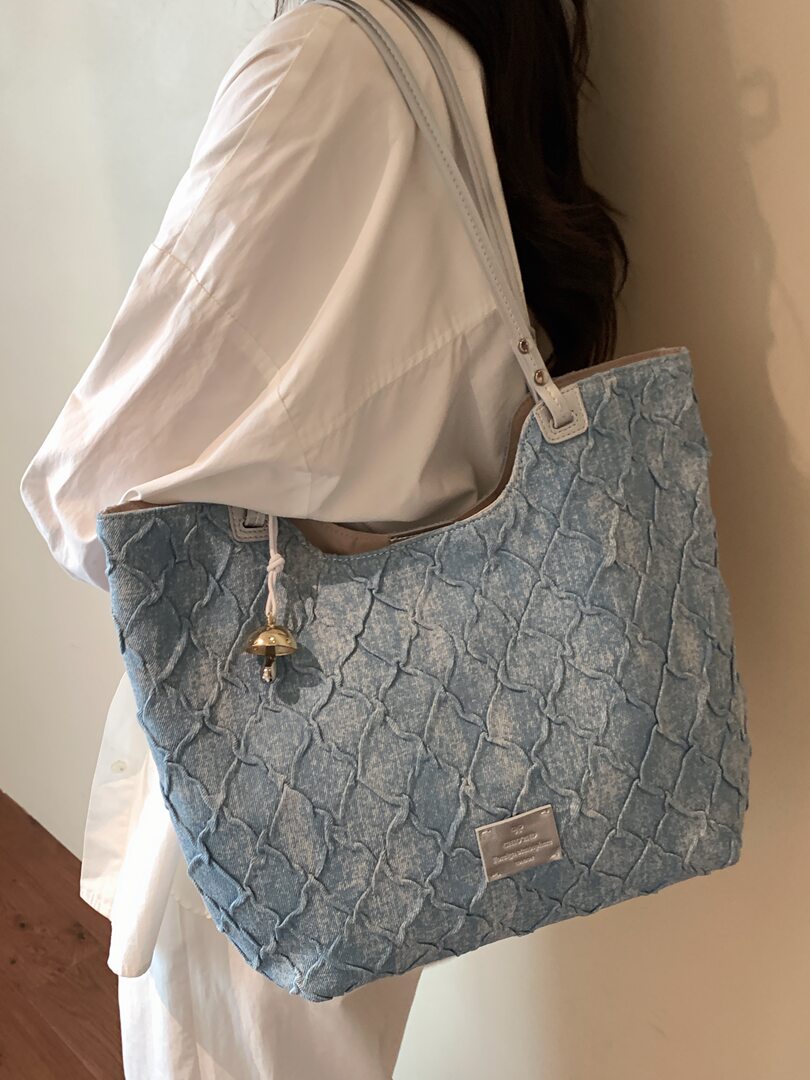 Blue textured tote bag worn over the shoulder on a person