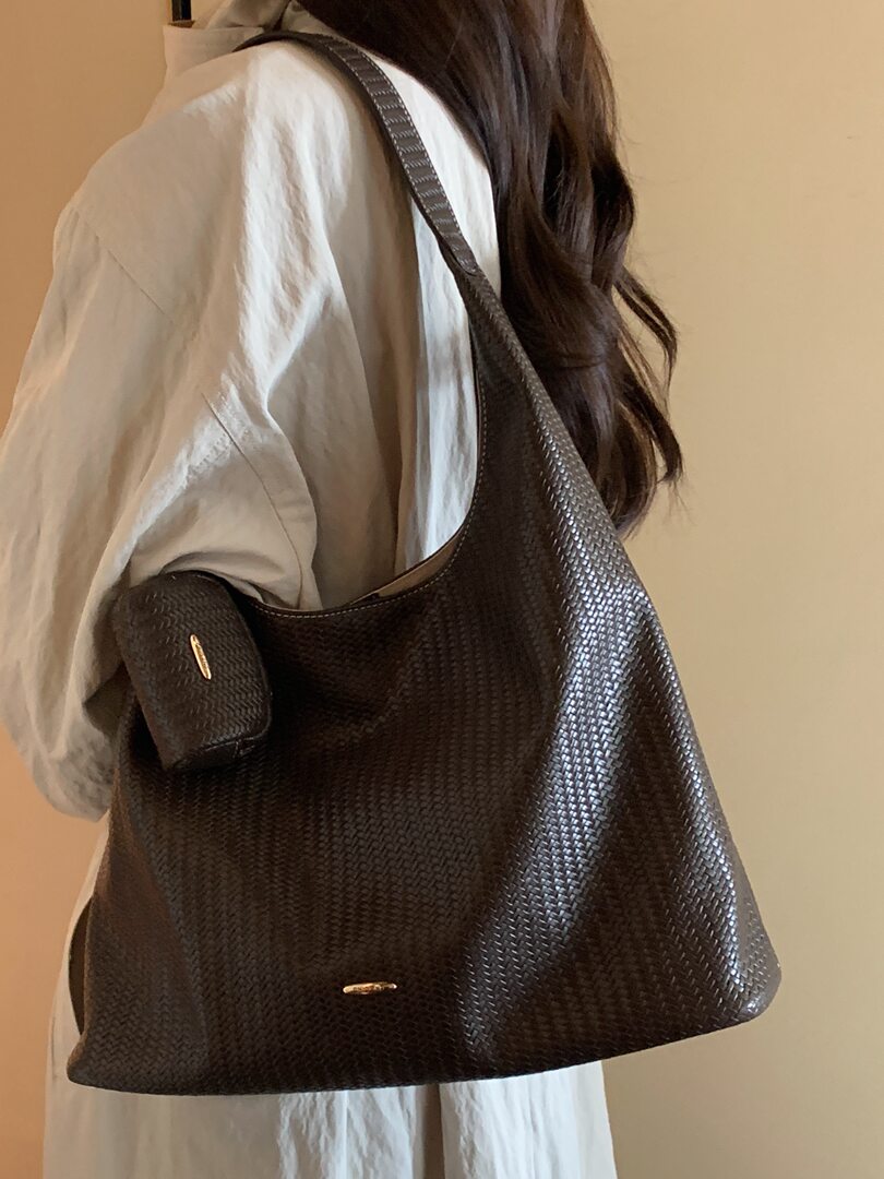 Black woven tote bag worn on a model