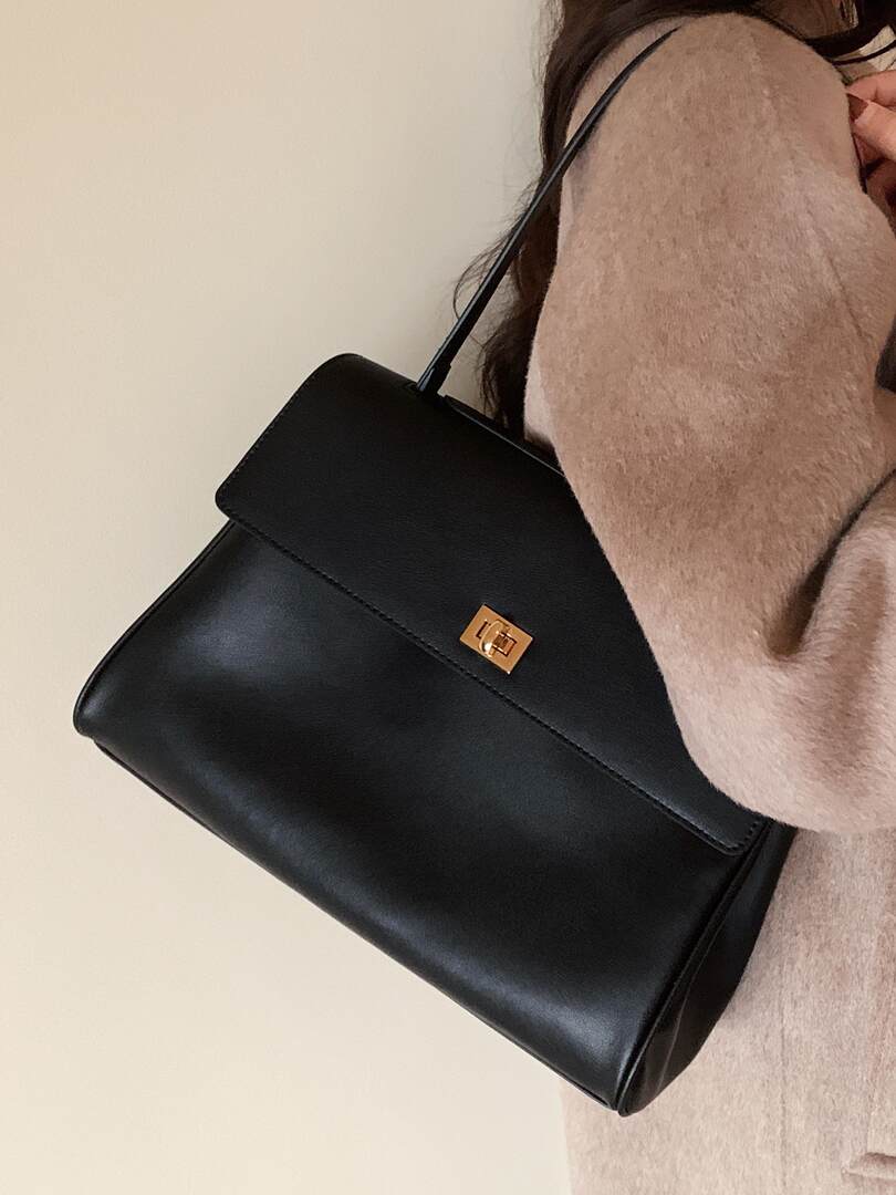 Black structured shoulder handbag worn on a person