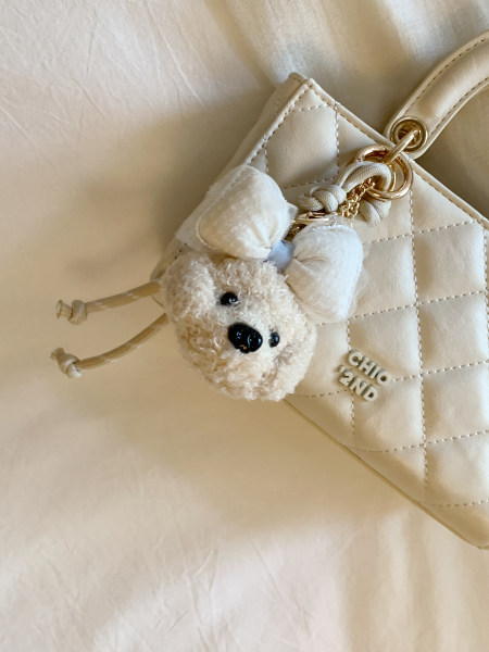 Cream quilted handbag with a teddy bear charm and gold hardware