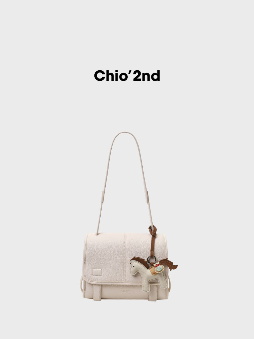 Cream shoulder handbag with a horse charm on a white background