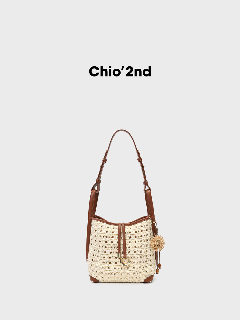 Crochet shoulder bag with brown faux leather trim and tassel charm on a plain background