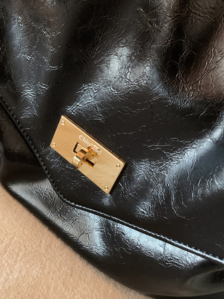 Black textured leather handbag with gold clasp hardware