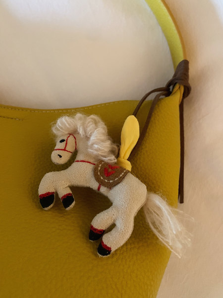 Small decorative horse charm attached to a yellow bag