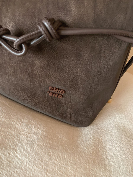 Close-up of a brown textured drawstring handbag with logo detail