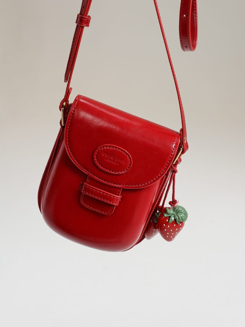 Red leather mini shoulder bag with strawberry charms on a white background