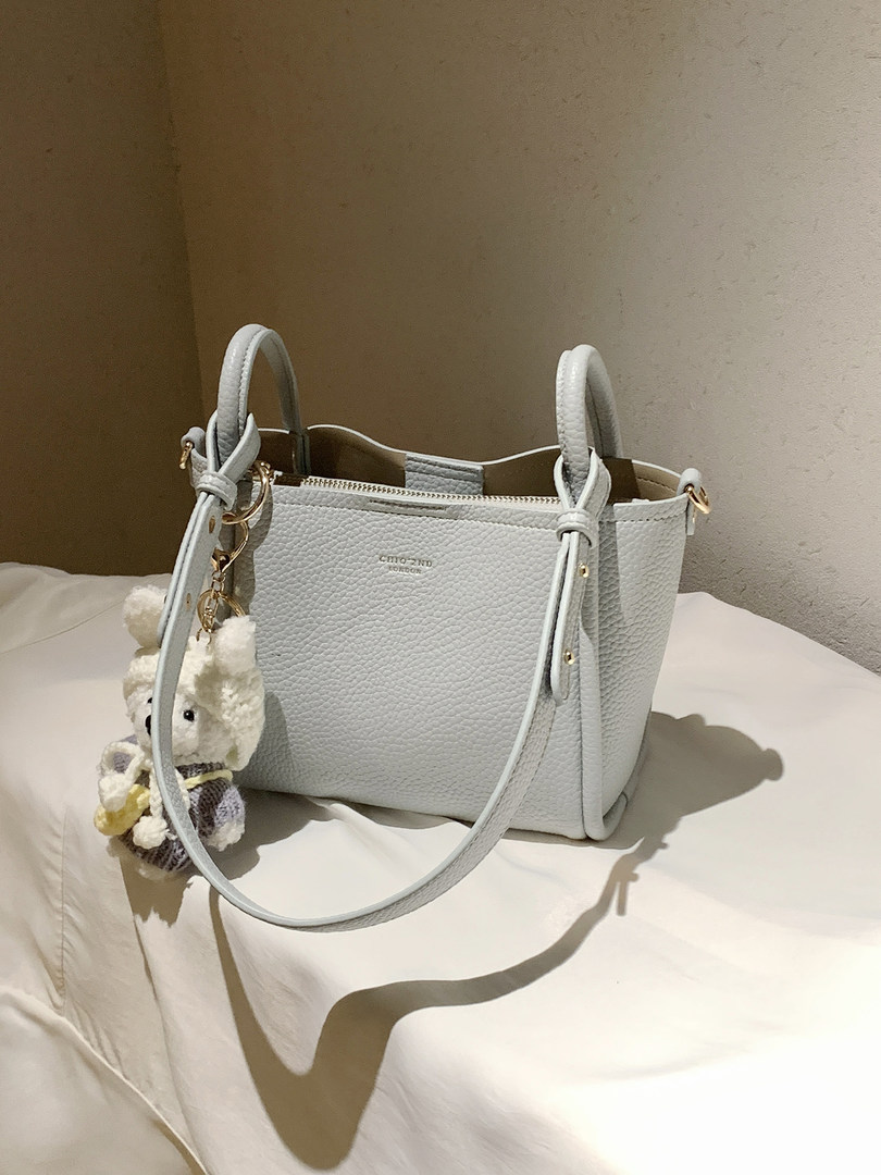 Light gray textured handbag with shoulder strap and teddy charm