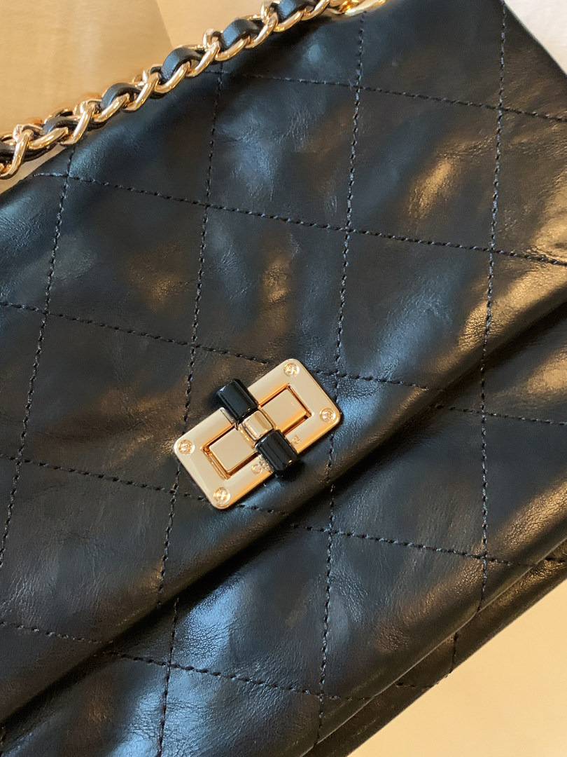 Close-up of a black quilted chain handbag with gold clasp