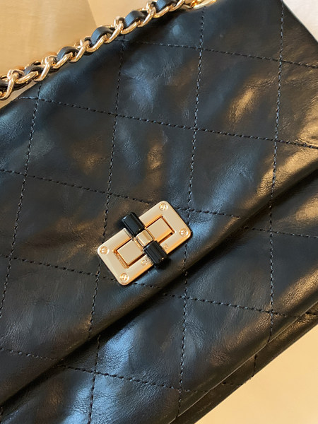 Close-up of a black quilted chain handbag with gold clasp