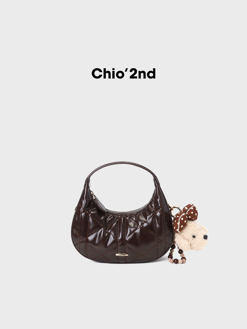 Dark brown quilted handbag with a teddy bear charm on a white background