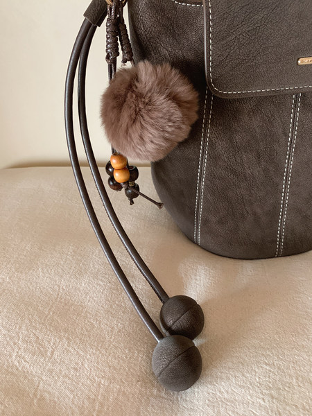 Dark brown leather bucket bag with pom-pom charm and beaded drawstrings