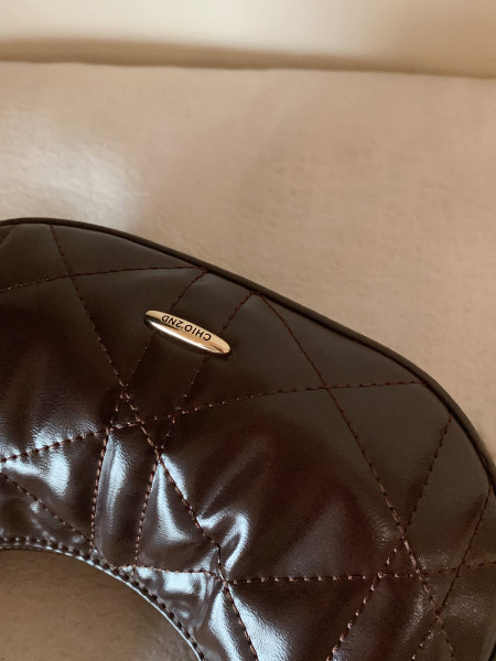 Close-up of a dark brown quilted leather handbag with metal logo detail