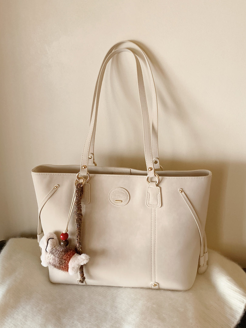 Beige leather tote handbag with long handles and charm