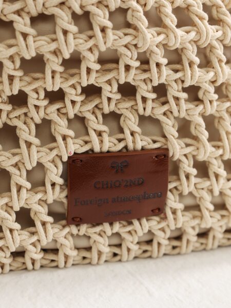 Close-up of a woven straw bag with a leather brand tag