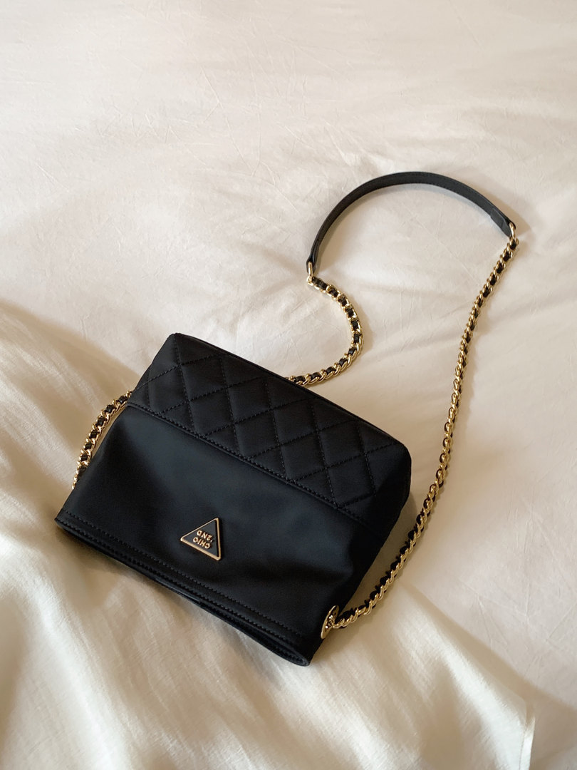 Black quilted chain-strap handbag on a light fabric surface