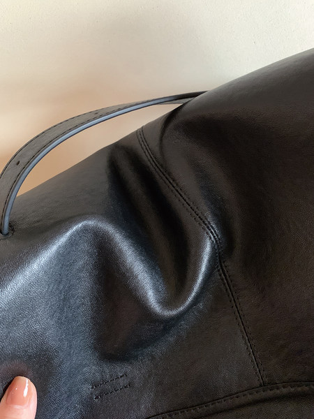Close-up of a black leather handbag with a curved handle