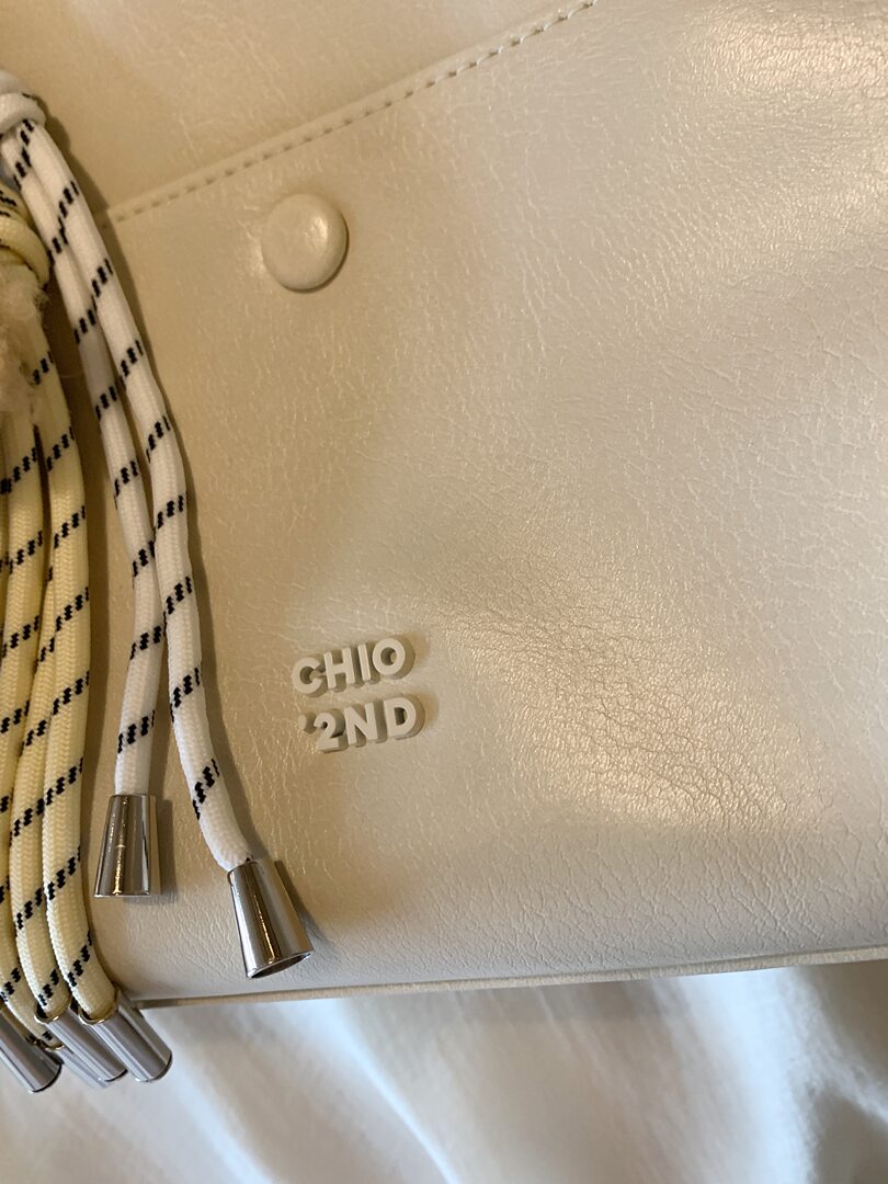 Cream textured handbag with braided rope straps and metal tips