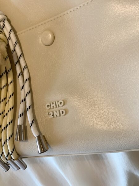 Cream textured handbag with braided rope straps and metal tips