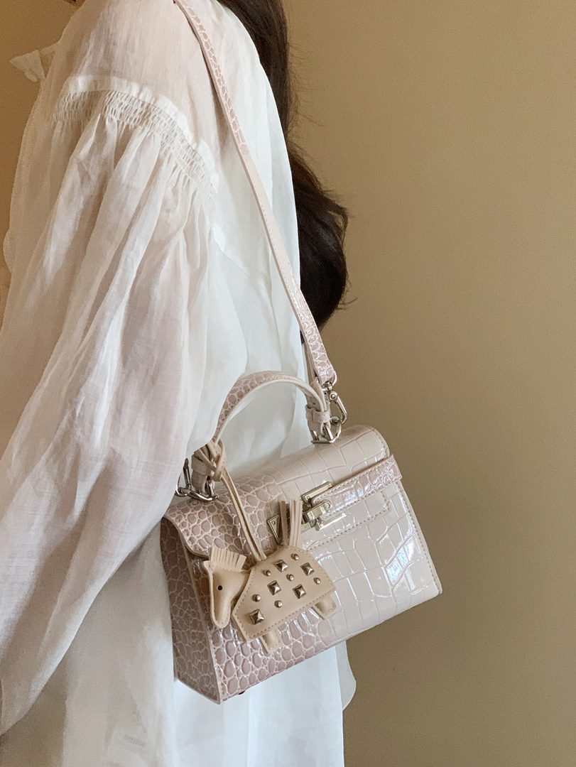 Light pink crocodile-embossed handbag worn over a white blouse