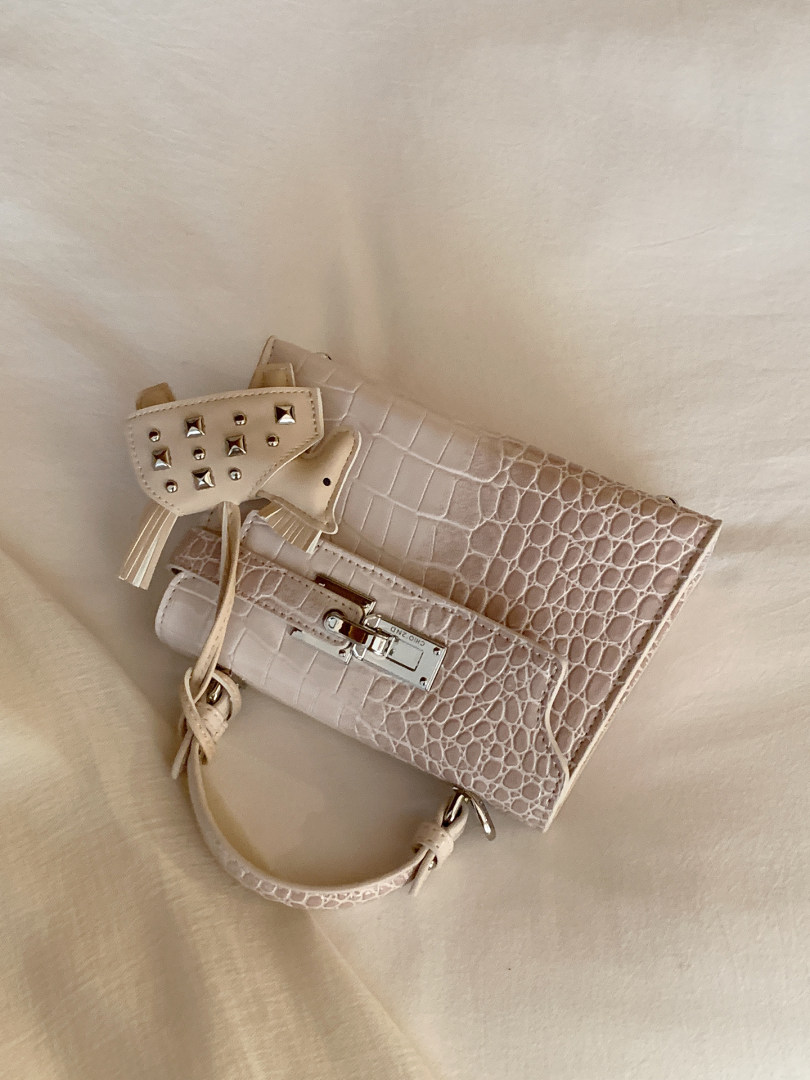 Cream crocodile-textured handbag with metallic clasp and studded flap