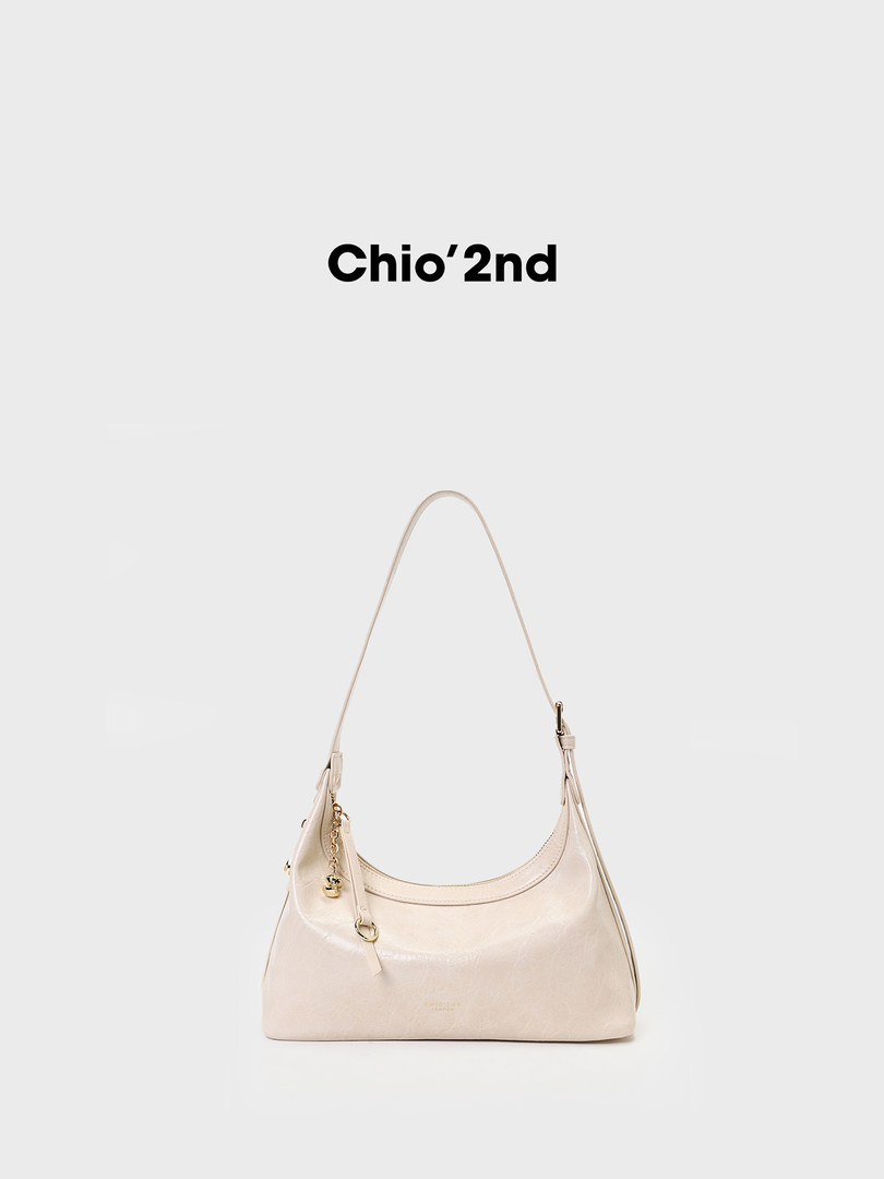 Cream shoulder handbag with a long strap and gold hardware on a white background
