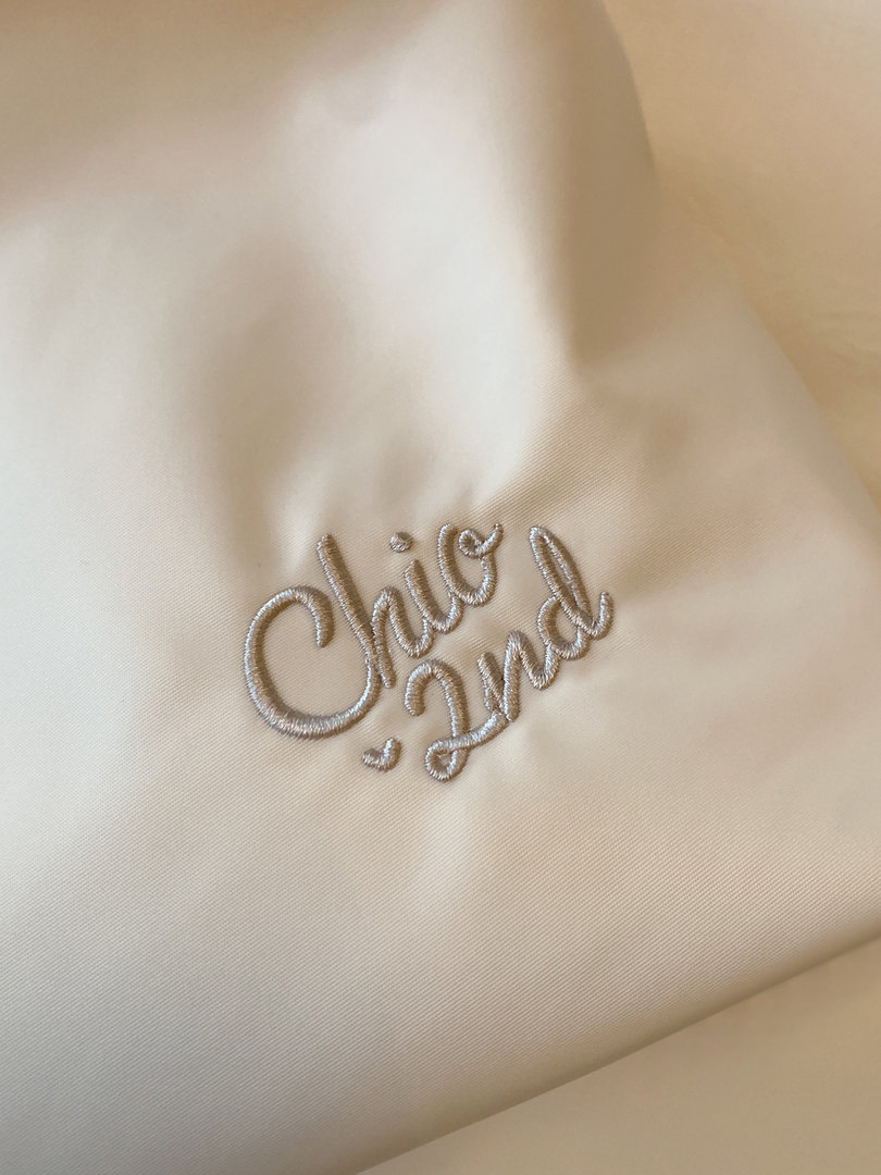 Close-up of cream satin fabric with embroidered logo text