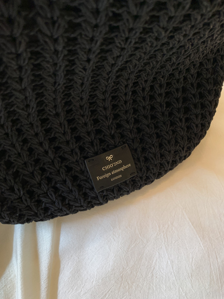 Black knitted fashion item with a brand label on a white surface