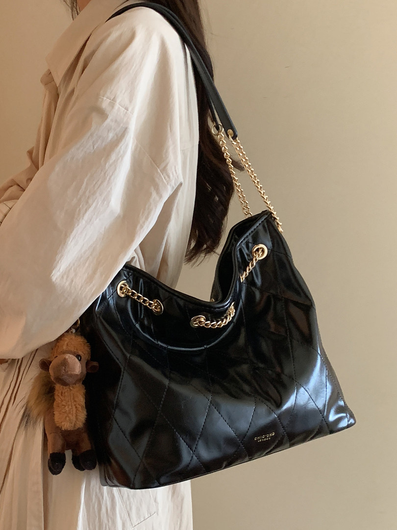 Black quilted chain-strap shoulder bag worn by a model
