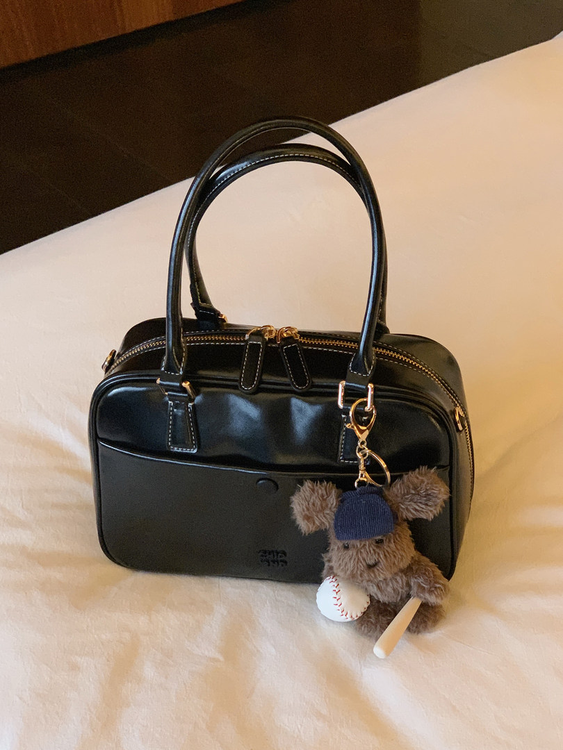 Black leather handbag with gold hardware and a teddy bear keychain
