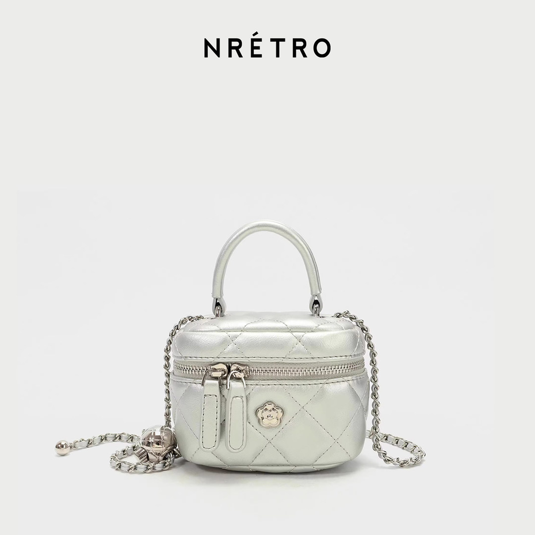 Silver quilted mini handbag with chain strap and top handle on a white background