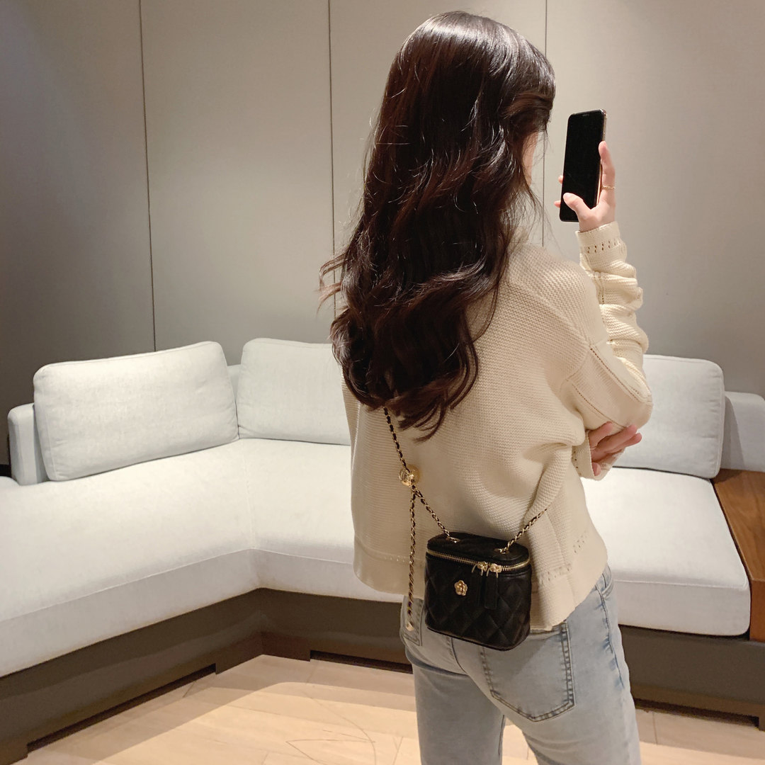 Woman wearing a cream knit sweater with a black mini crossbody bag