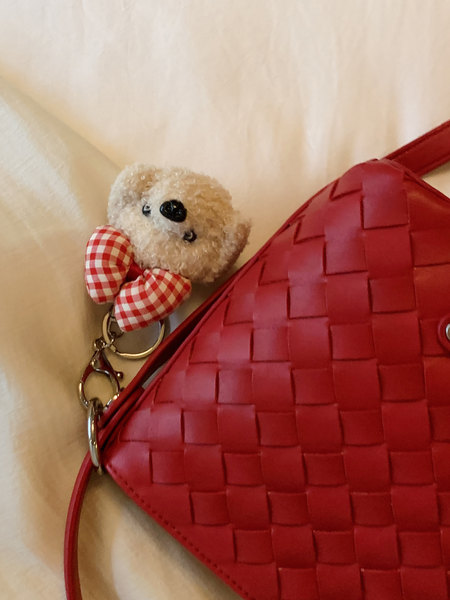 Red woven handbag with a teddy bear keychain charm
