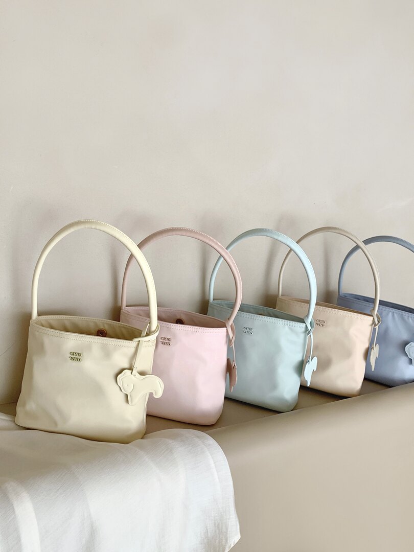 Pastel tote bags with long handles displayed on a couch