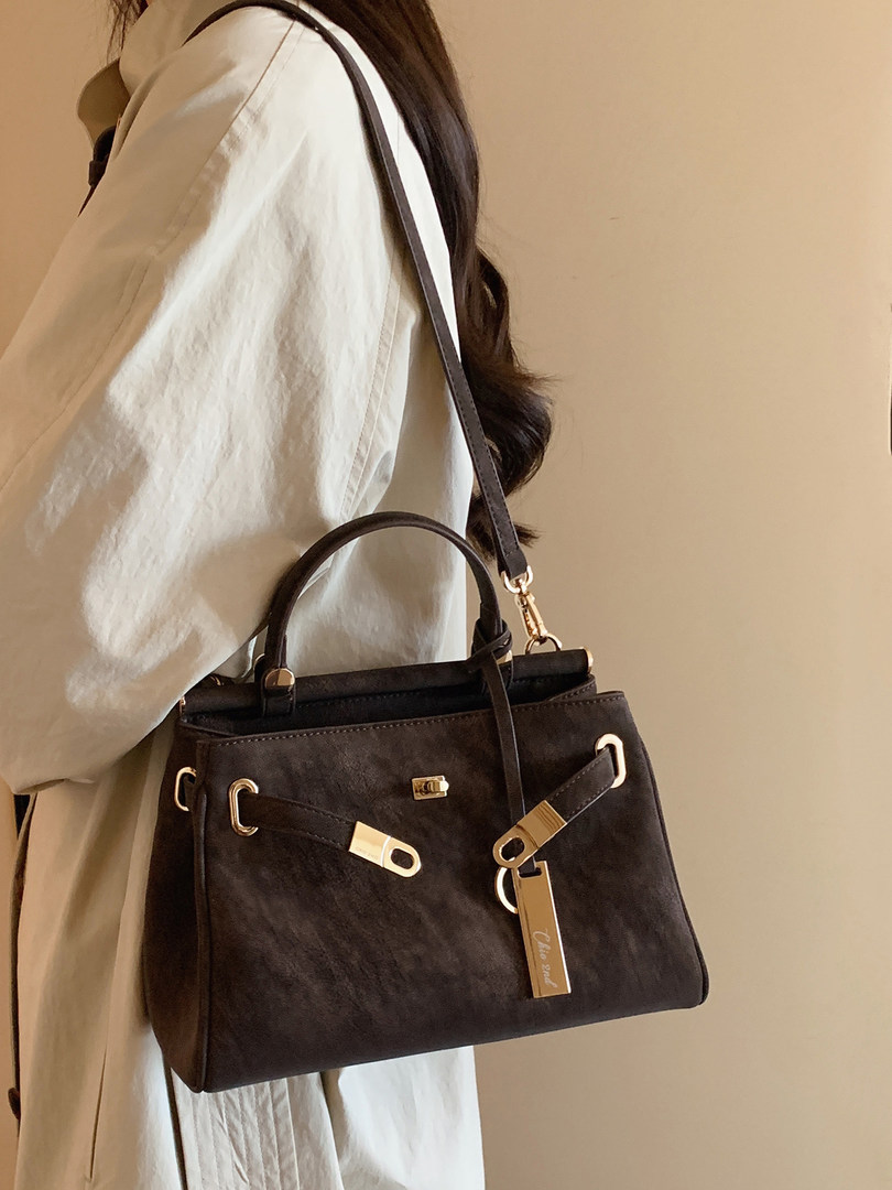 Black structured handbag worn crossbody on a model