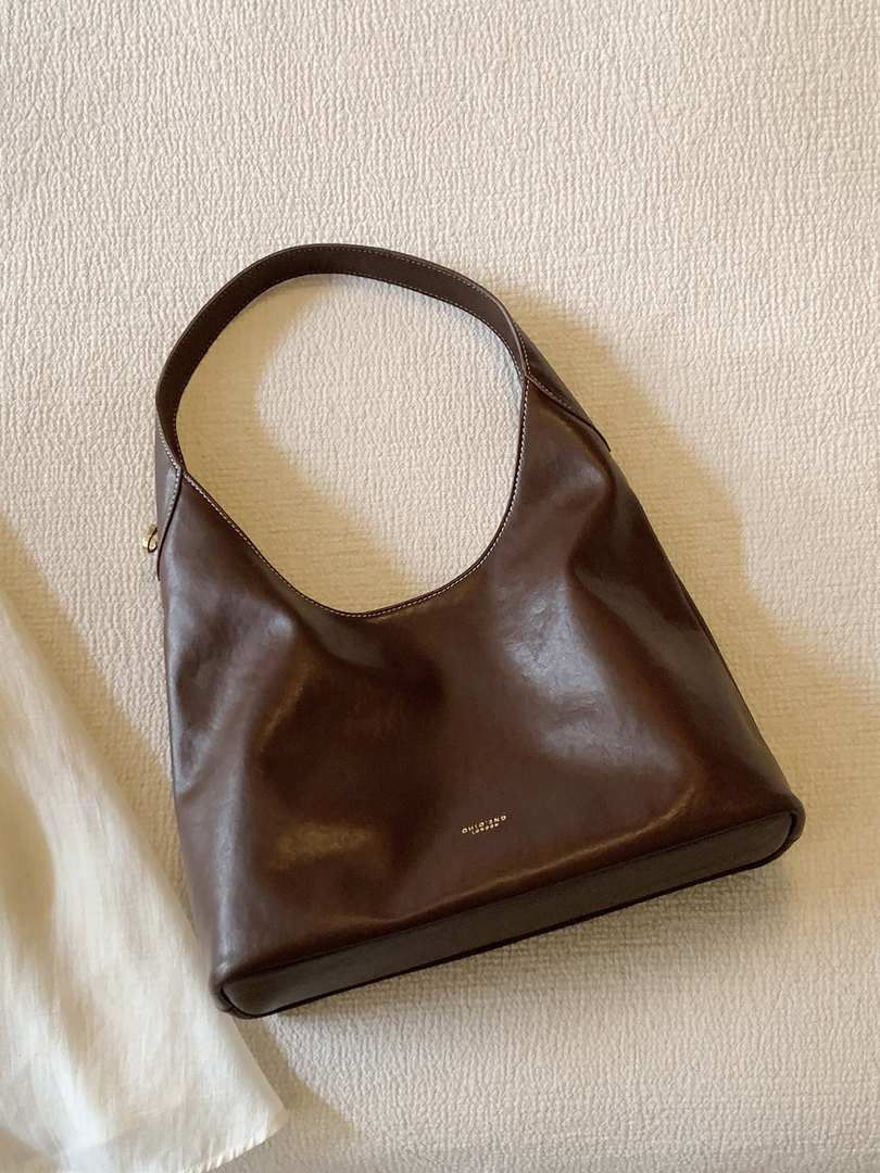 Brown leather shoulder bag on a light textured background