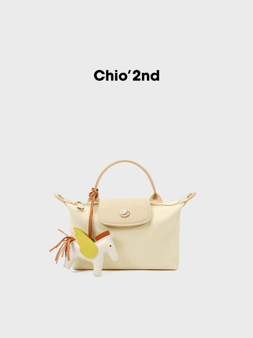 Cream handbag with decorative charm on white background