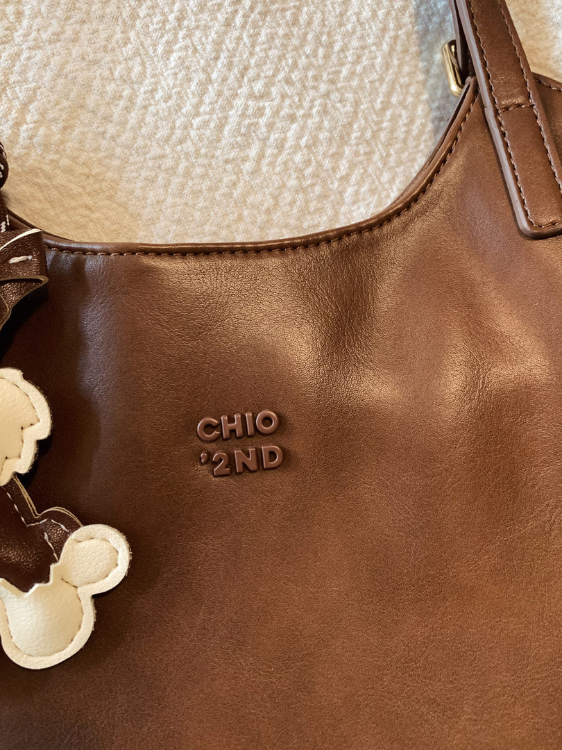 Brown leather handbag with a floral charm and CHIO'2ND logo