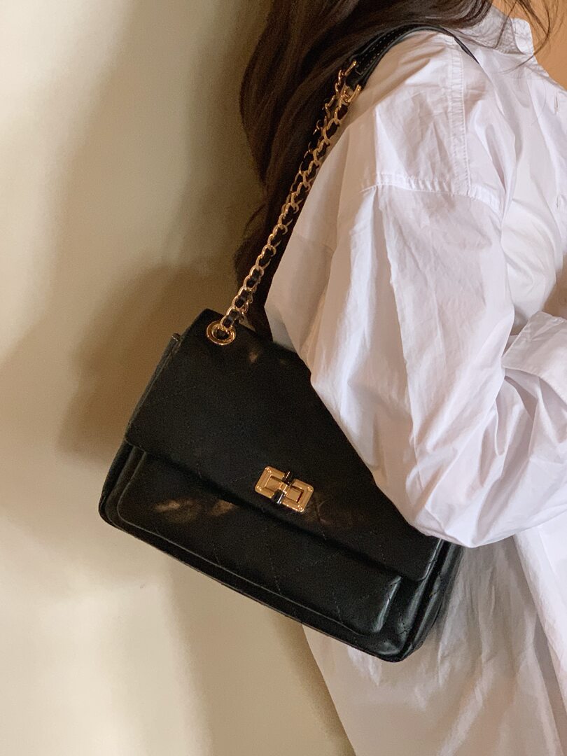 Black leather chain-strap handbag worn with a white outfit