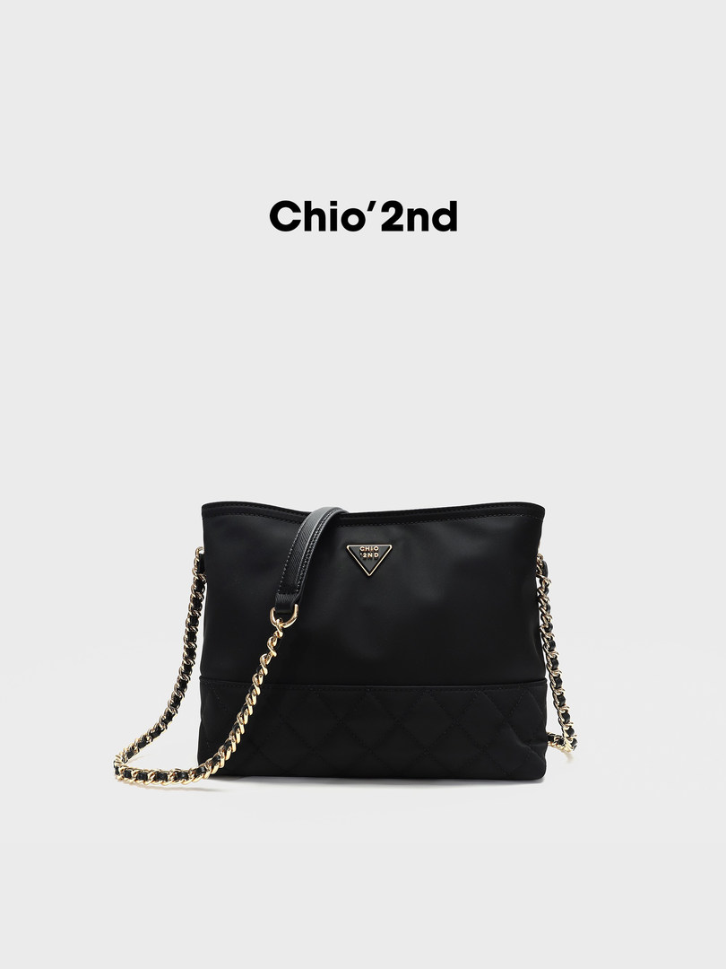 Black quilted handbag with gold chain strap on a white background