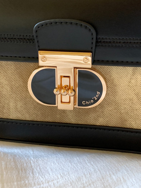 Close-up of a black and beige handbag with a gold clasp